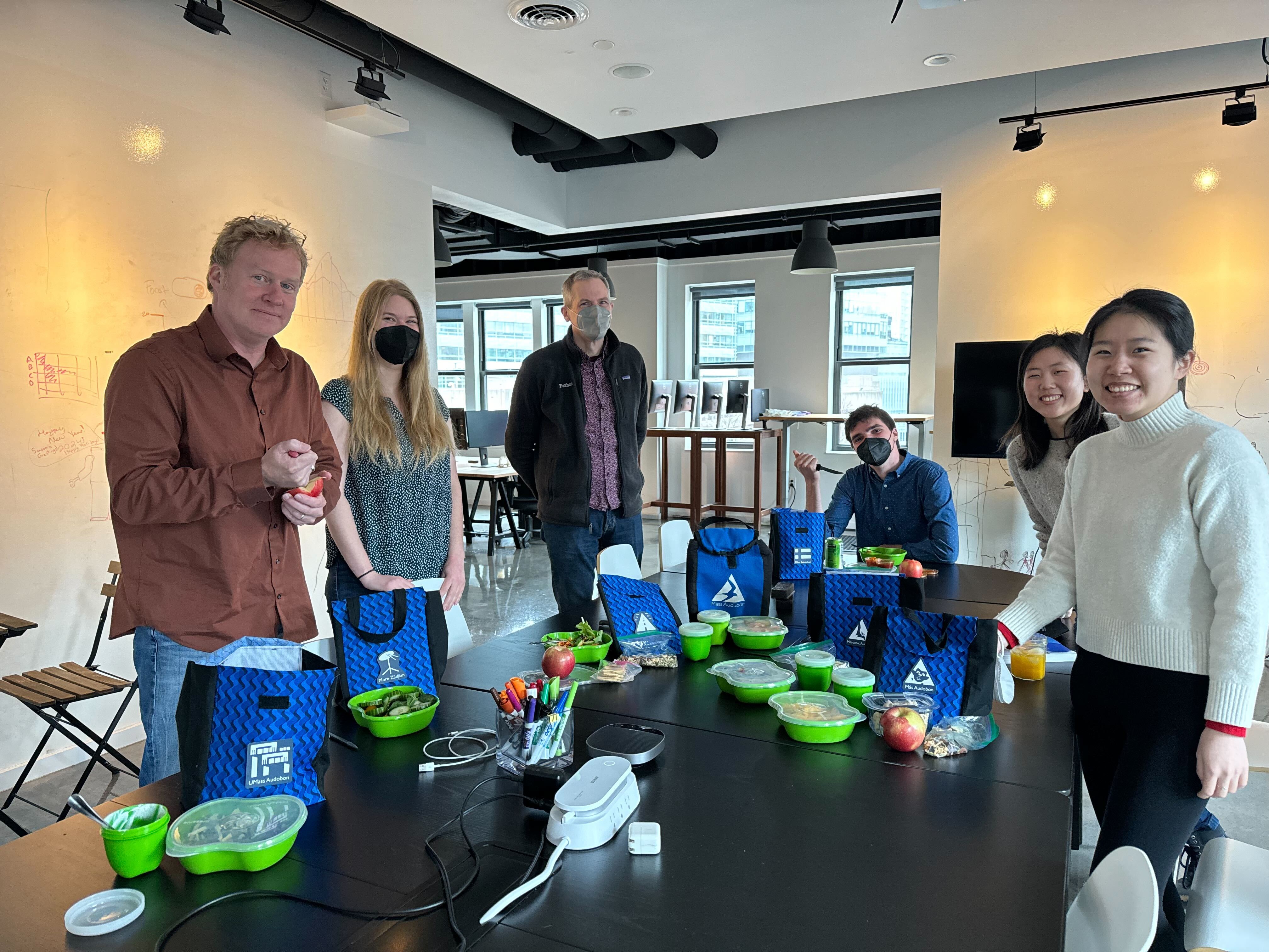 The Fathom team surrounds the lunch table, each with a matching lunchbag, meal, and tupperware container.